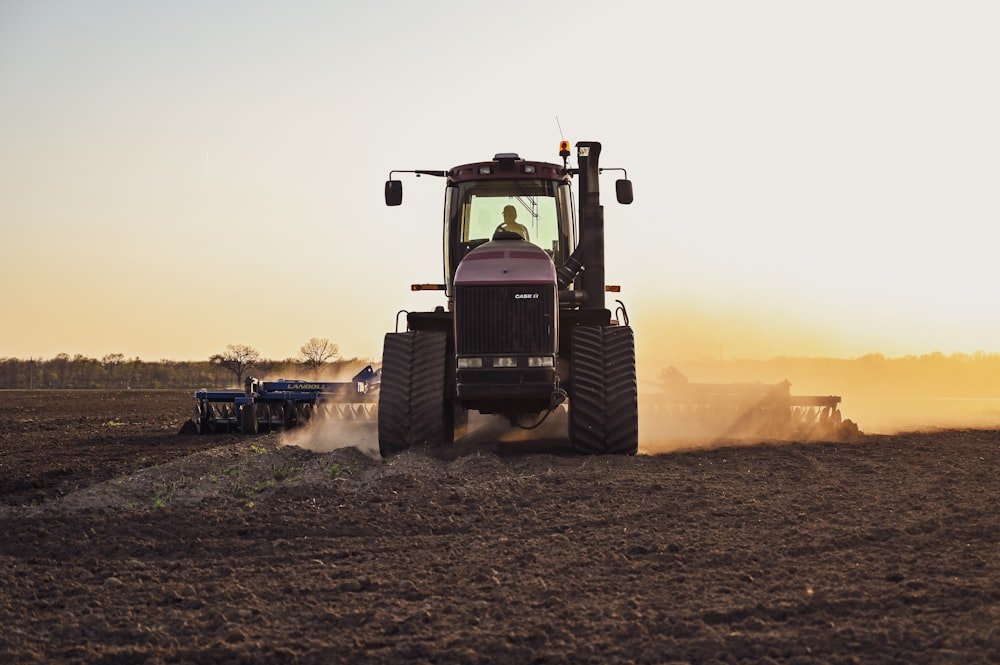 Trator agrícola em operação no campo ao entardecer